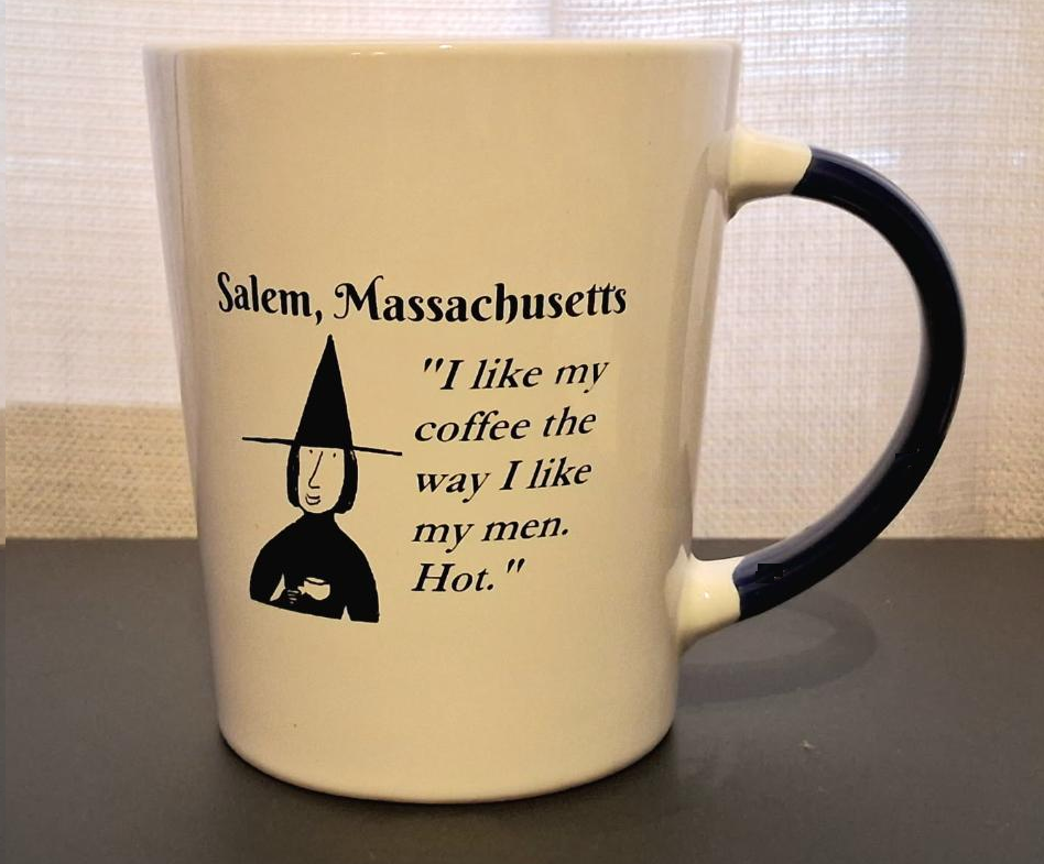 Salem, Massachusetts "I like my coffee the way I like my men. Hot." White, ceramic, 15oz coffee mug with black handle and interior.